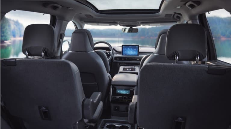 2019 Lincoln Navigator in Burgundy Velvet towing boat on uphill road near water