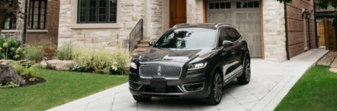 Una Lincoln Nautilus 2019 en negro infinito estacionada en la entrada para auto de una casa grande
