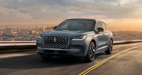 La SUV Lincoln Corsair® circulando por un puente de una autopista con la ciudad en segundo plano.