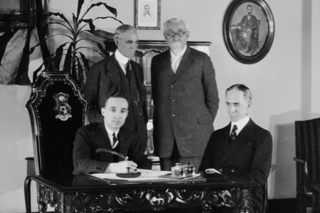 Four men are shown here around a table signing the purchase document for Lincoln in 1922