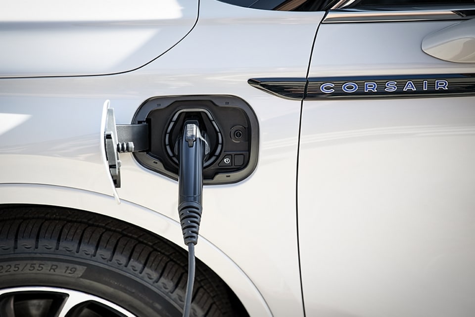 An electric charger is plugged into a 2021 Lincoln Corsair Grand Touring port below the nameplate near the front drivers side door and wheel well.