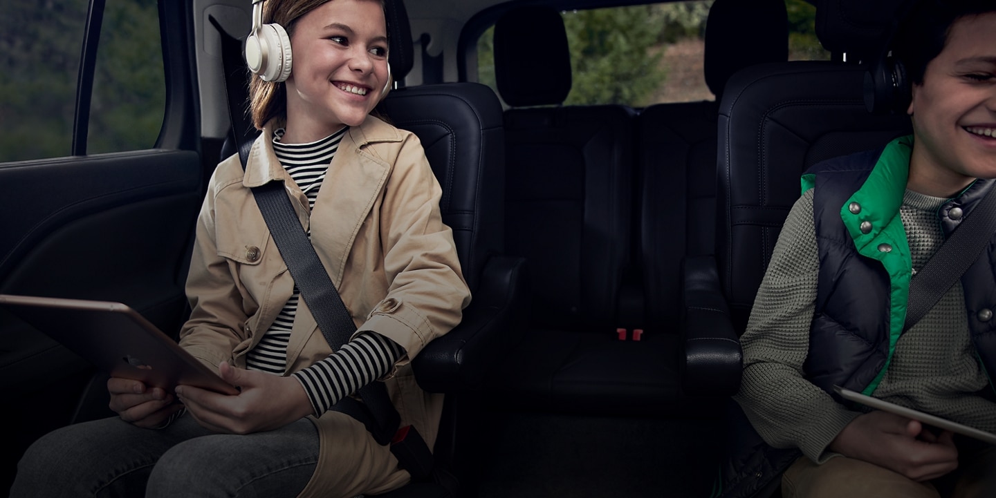 se muestran niños riéndose mientras usan tablets en los asientos de una Lincoln Aviator 2022