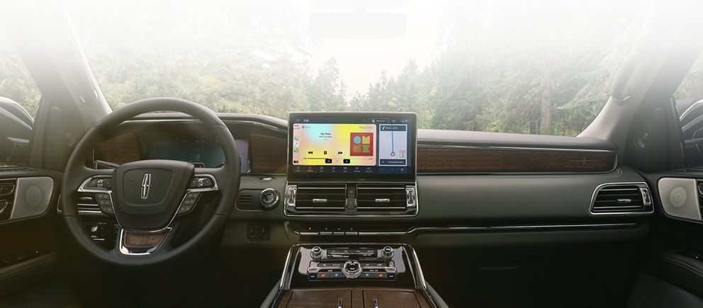El interior de la cabina delantera de una SUV Lincoln Black Label Navigator® 2023 en el tema Central Park hace alarde de su tecnología y de sus controles.