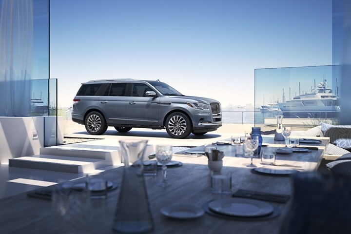 Una SUV Lincoln Navigator® 2024 estacionada cerca del mar muestra el tema Lincoln Black Label Yacht Club.