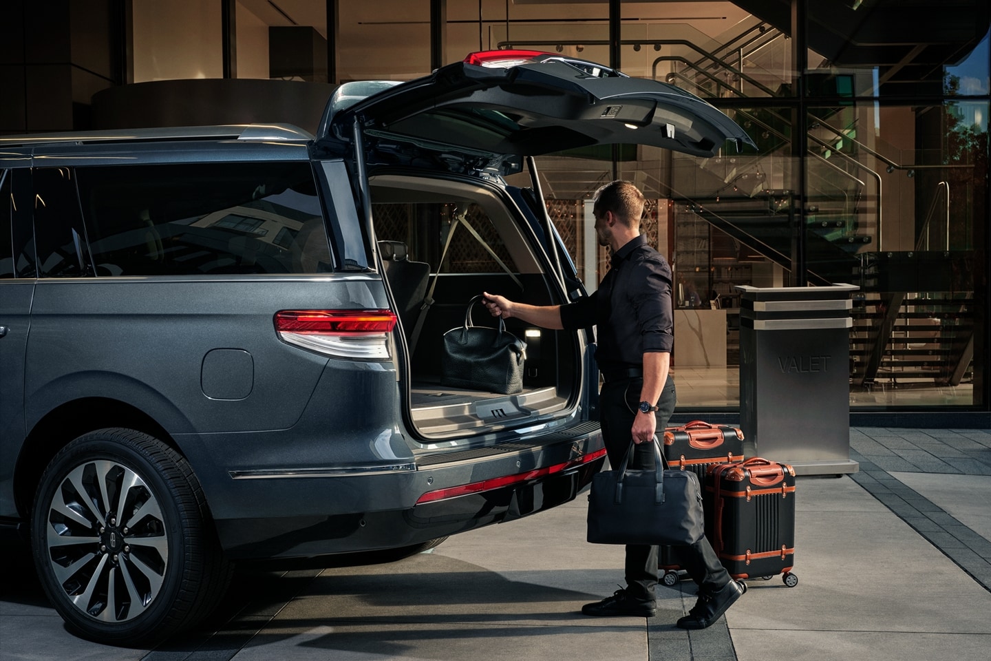 A man loading a bag into the back of a Lincoln vehicle.