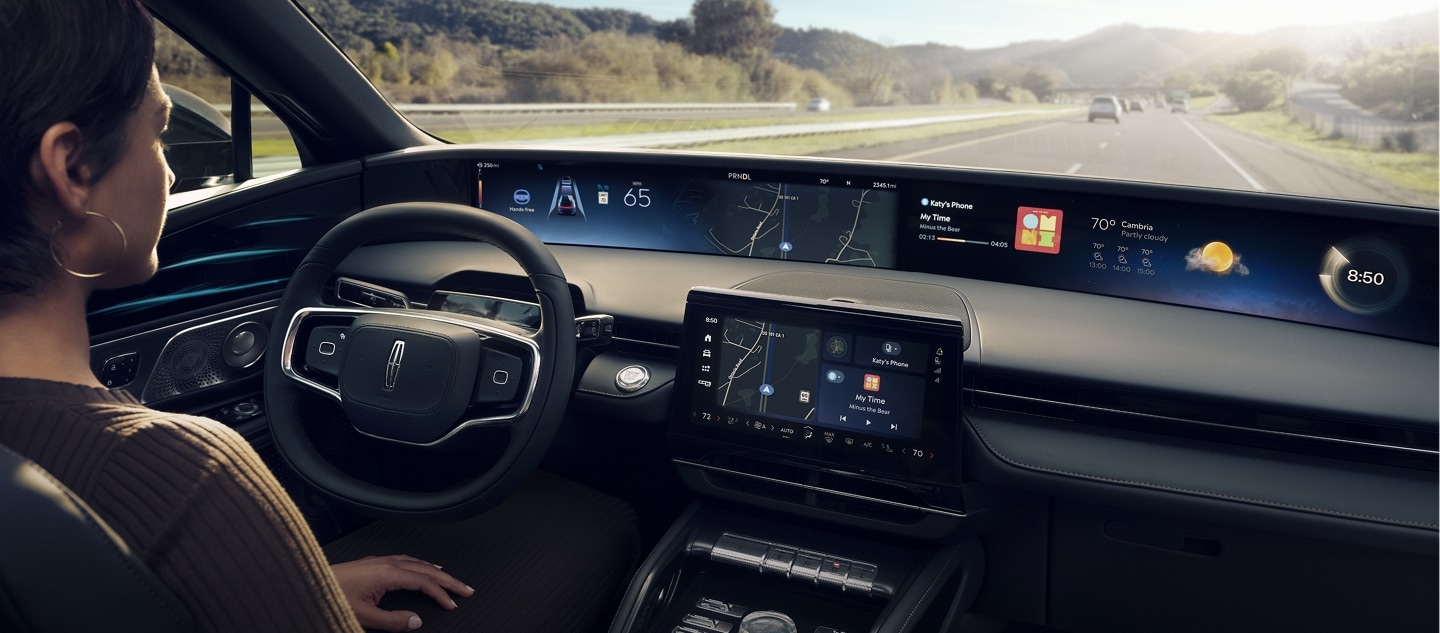 A woman is shown driving Lincoln Nautilus SUV hands-free using Lincoln BlueCruise on a highway.