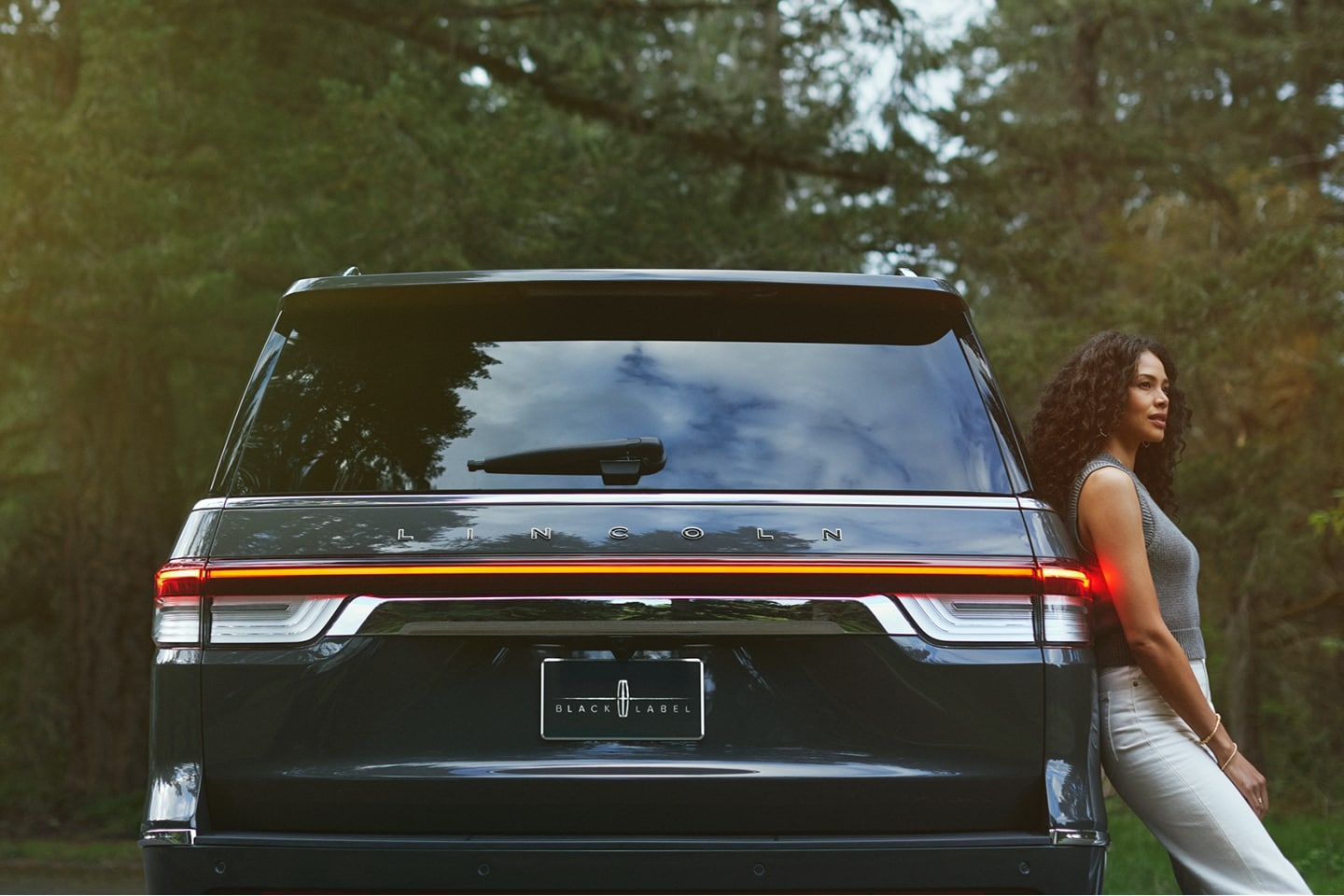 A woman relaxes against the side of a 2023 Lincoln Black Label Navigator® SUV.