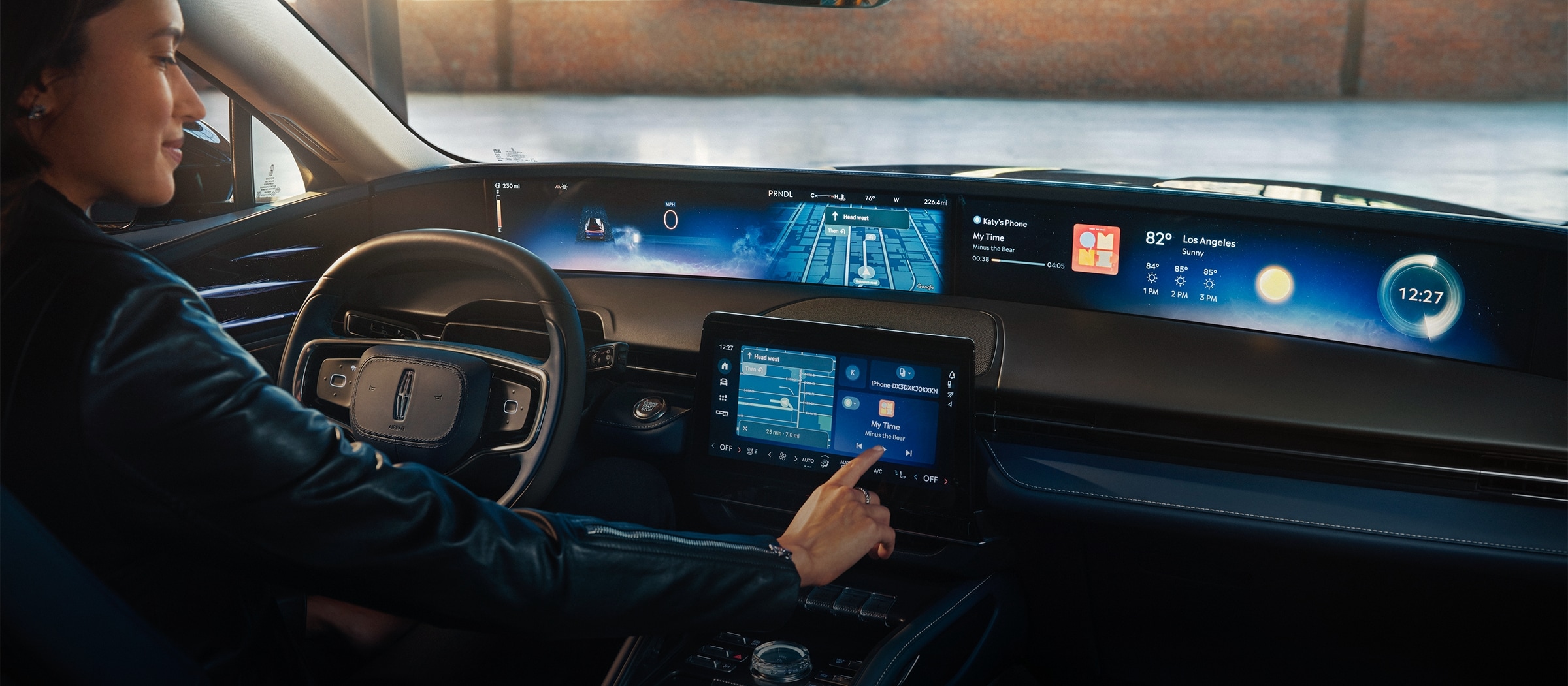 A woman is shown in the driver’s seat of a Lincoln Nautilus® SUV touching the center-stack display.