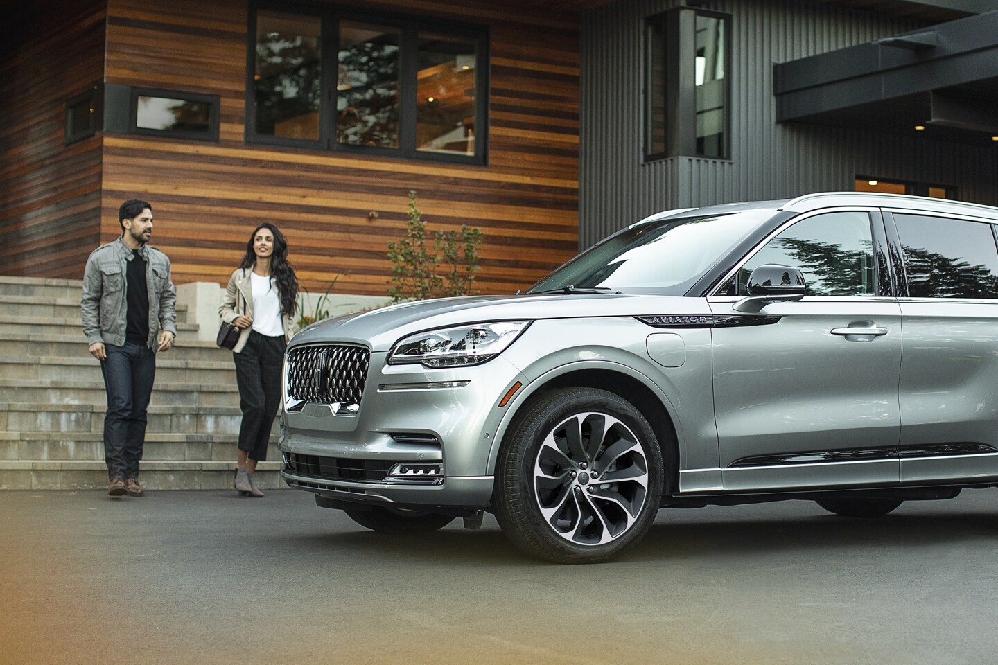 Two people are shown approaching a parked Lincoln Aviator