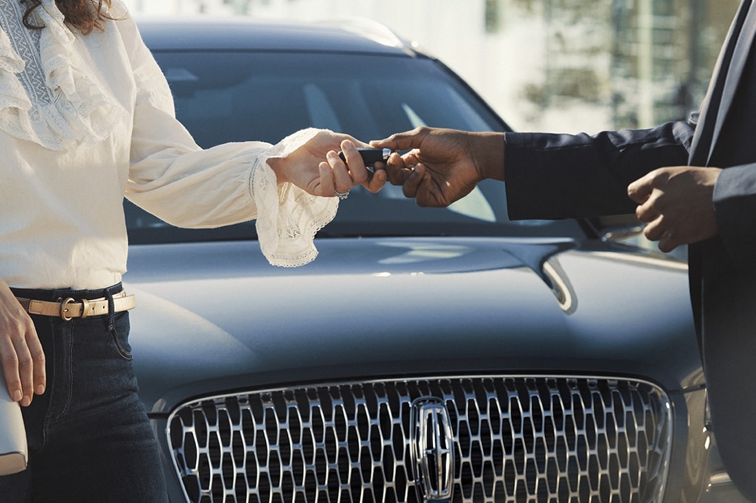 Un representante de Lincoln Pickup & Delivery devuelve las llaves de un automóvil a un cliente.