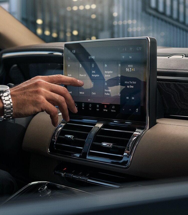 A man using the touchscreen on his Lincoln Navigator.