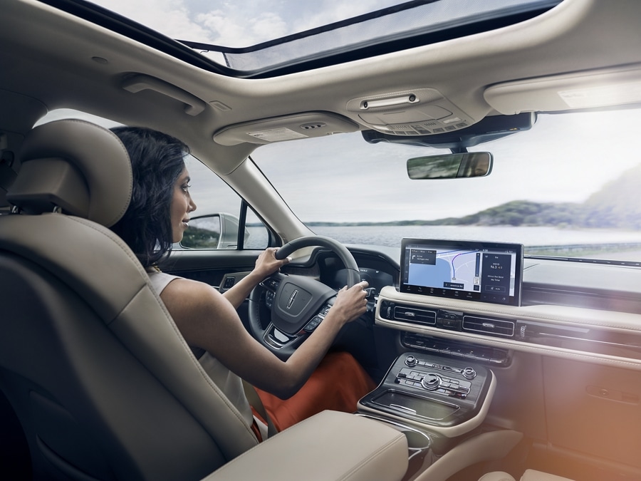 A person is shown driving a 2021 Lincoln Nautilus with the sync four navigation screen active