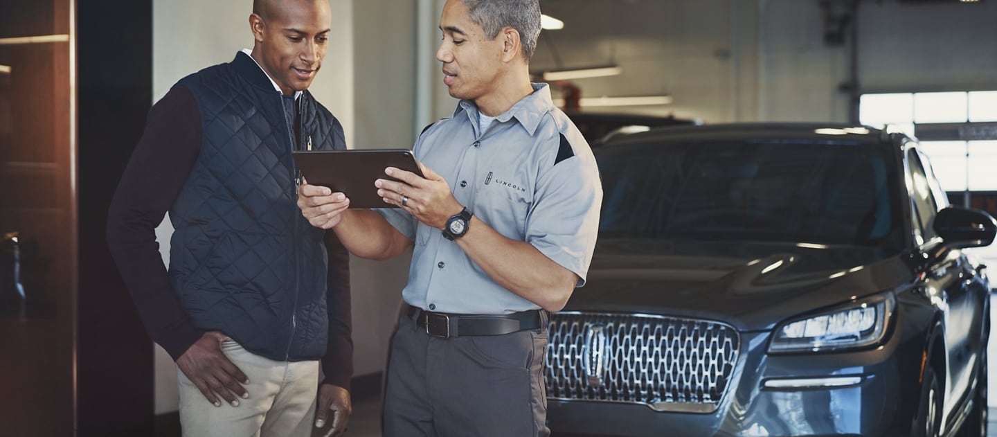 A Lincoln service representative is shown assisting a customer with his new Lincoln