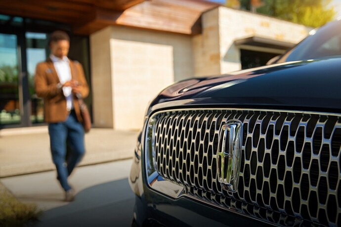 A man walking towards his Lincoln vehicle.