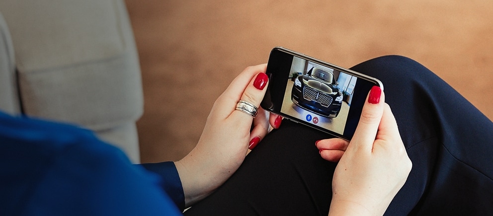 A woman looking at her phone of a private tour of a Licnoln vehicle.