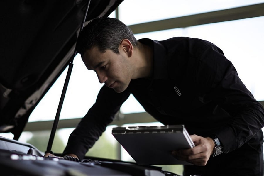 Man checking under the hood of a vehicle