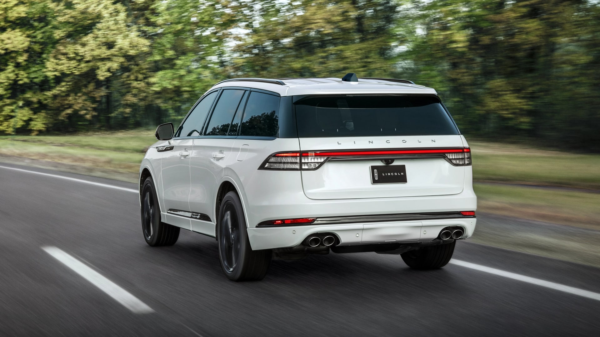 The rear of the 2025 Lincoln Aviator driving down a road.