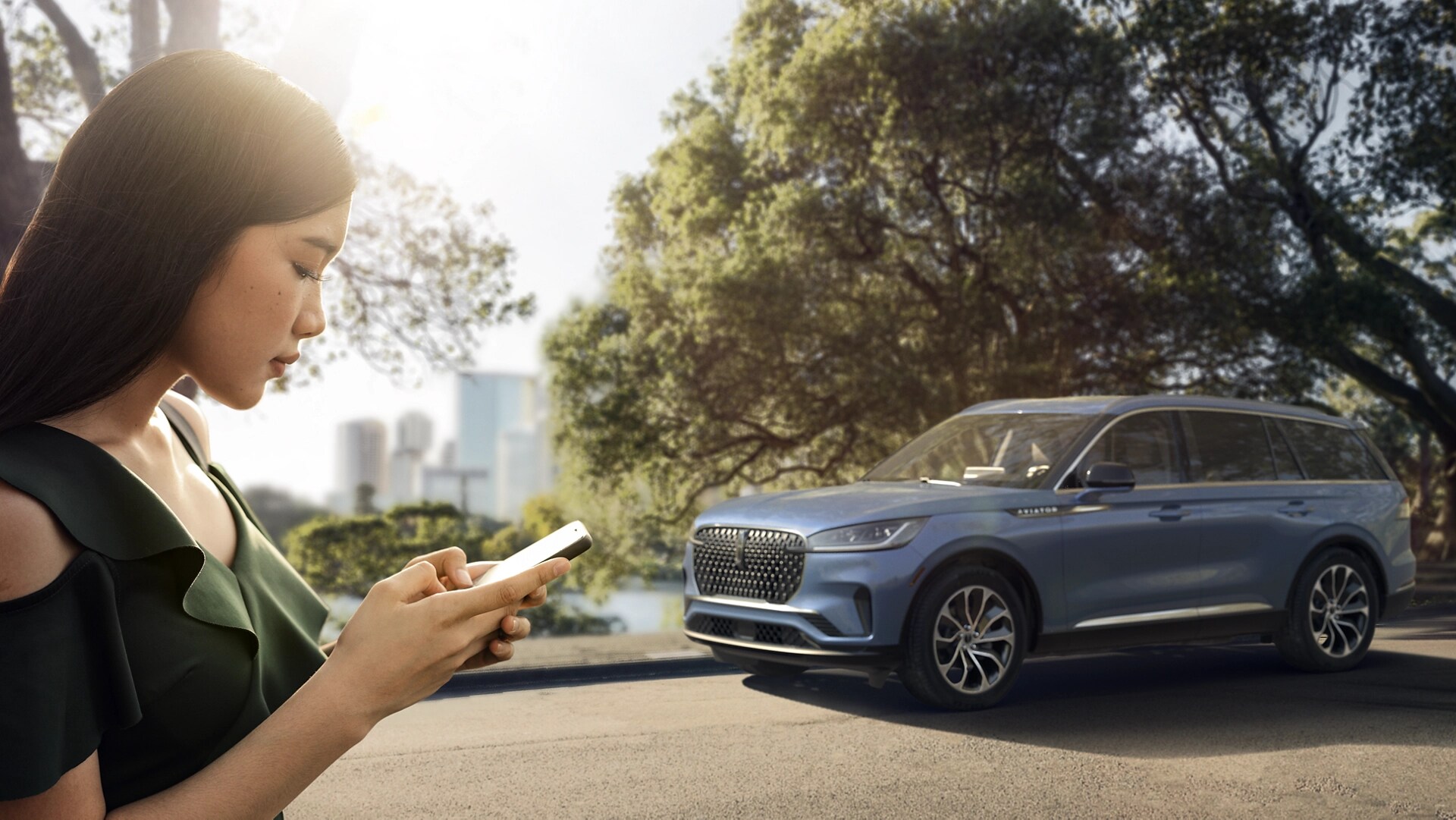 A person is shown using a smartphone in close proximity to a Lincoln vehicle.