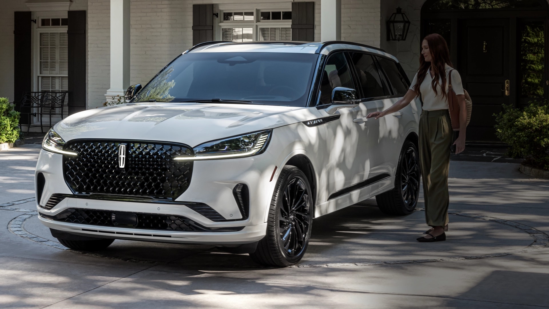 A person approaches a 2025 Lincoln Aviator® while holding a mobile phone.