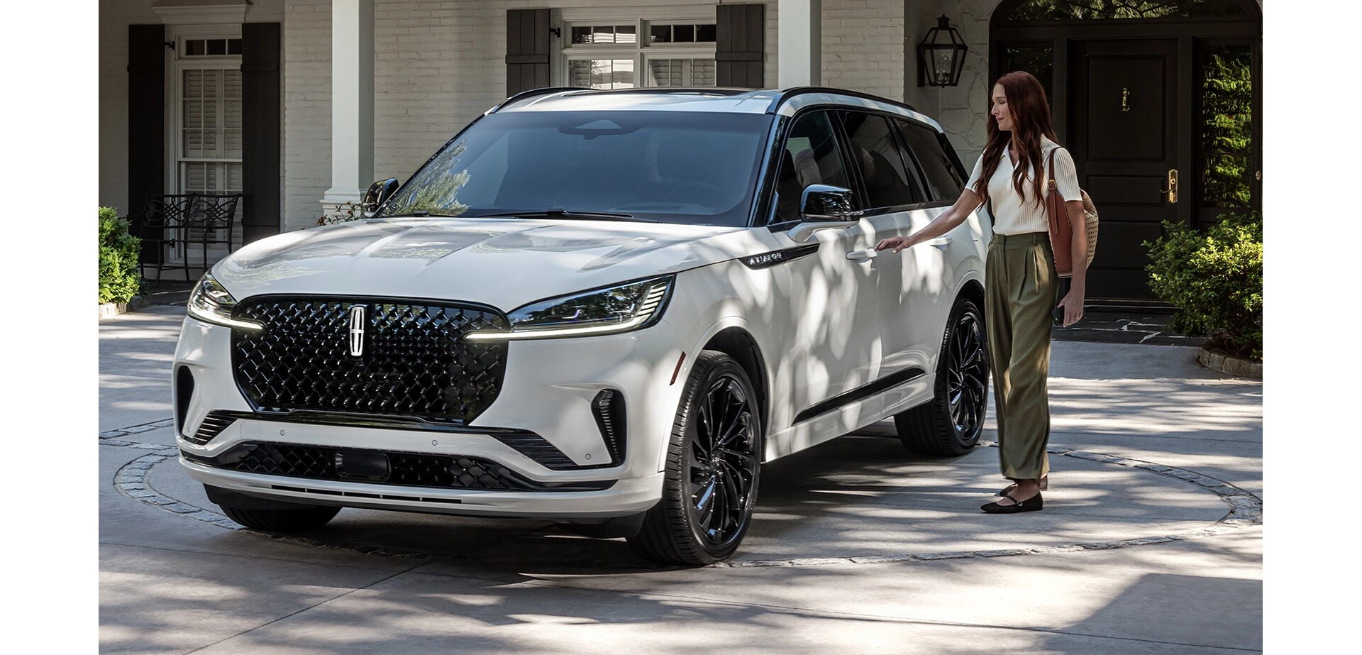 A person approaches a 2025 Lincoln Aviator® while holding a mobile phone.