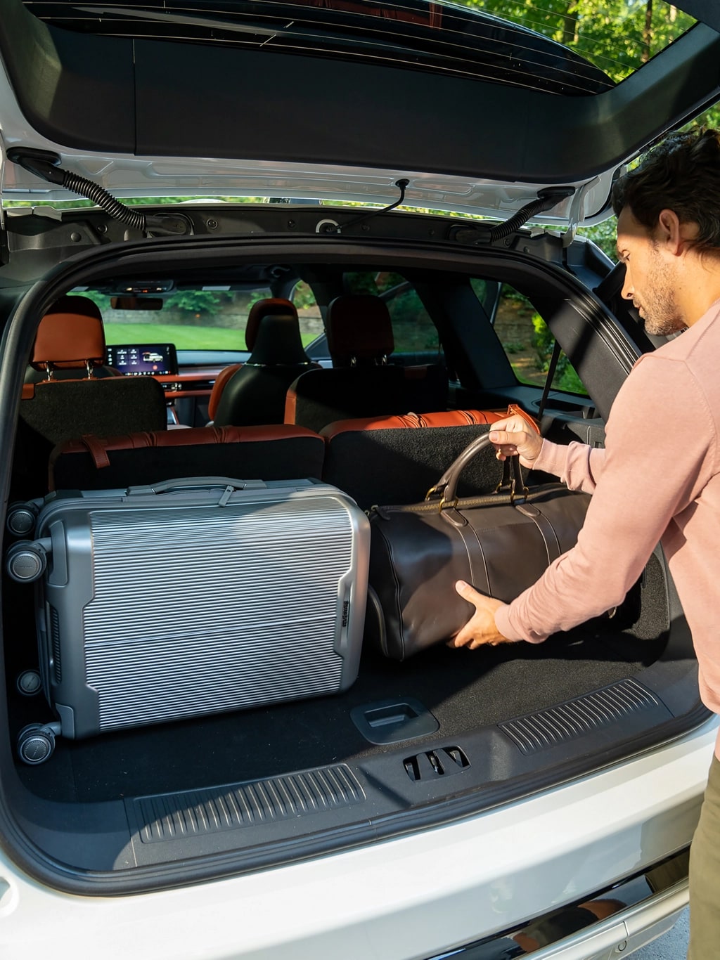 A man loads luggage into the rear of a 2025 Lincoln Aviator® SUV through the opened rear liftgate.