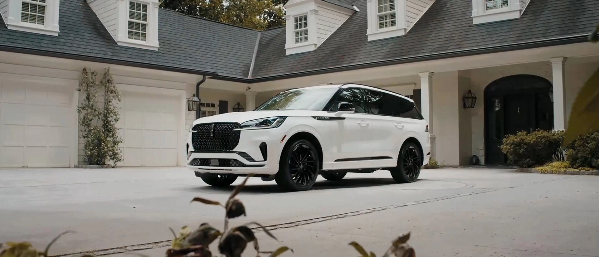 A 2025 Lincoln Aviator® SUV is parked in the driveway of a luxury home
