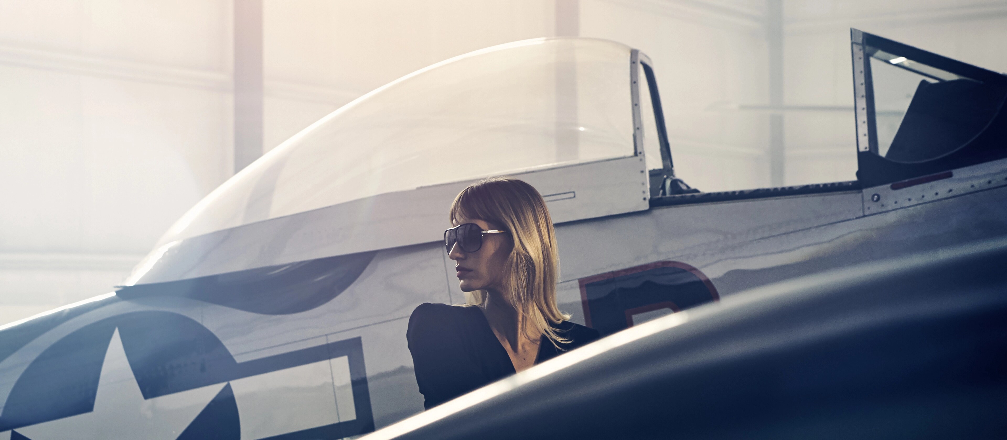 A woman is shown next to a vintage airplane to evoke the inspiration for the Lincoln Black Label Flight theme