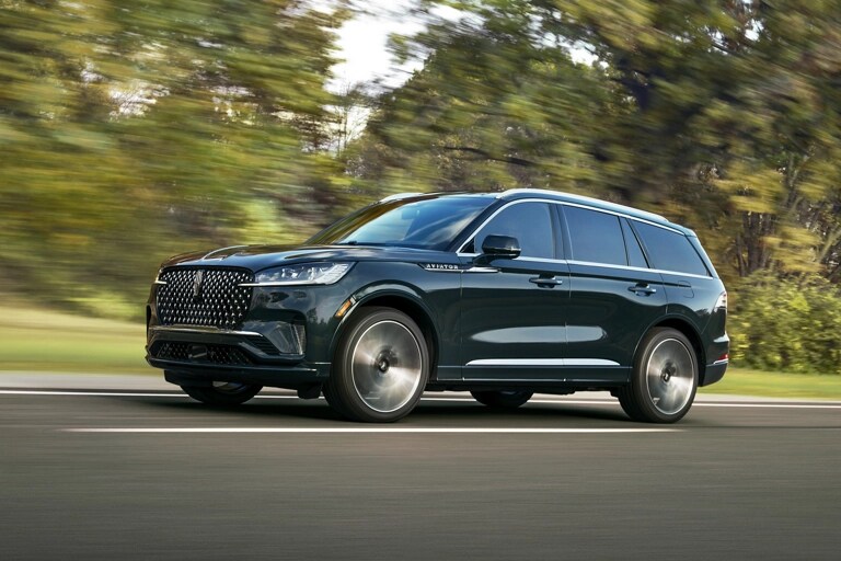 A 2026 Lincoln Aviator® SUV is shown driving on a forested road