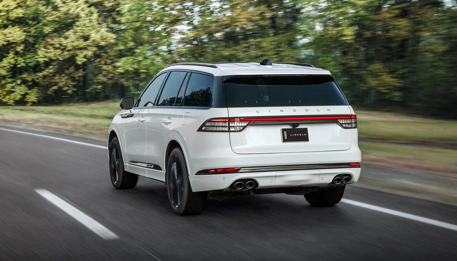A 2026 Lincoln Aviator® SUV is shown driving on a forested road