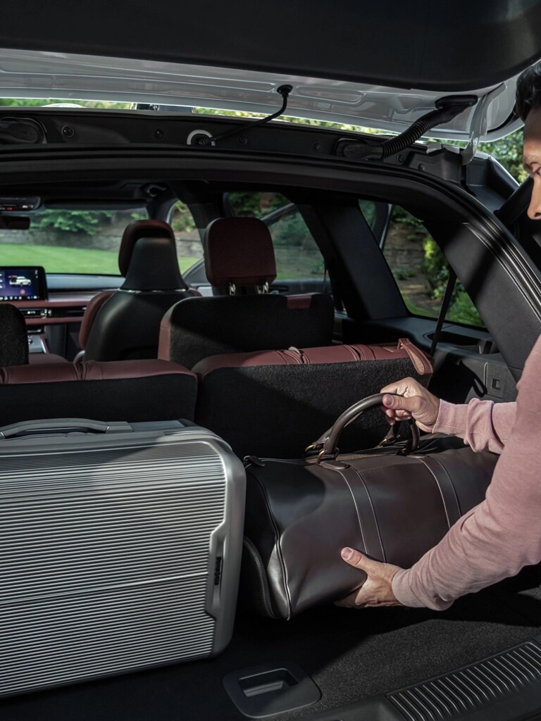 A person loads a leather bag into the rear cargo area of a 2026 Lincoln Aviator® SUV