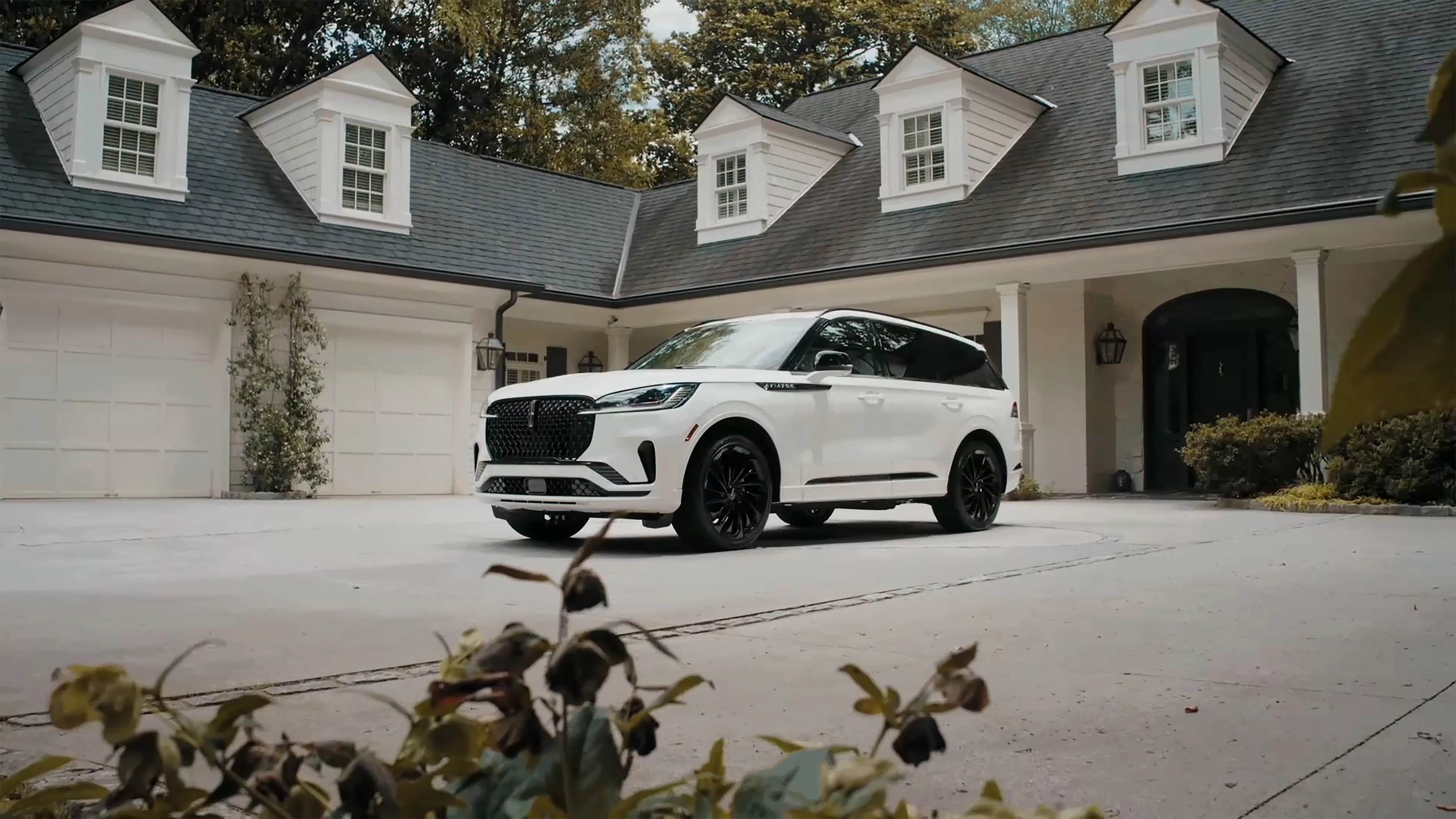 A 2026 Lincoln Aviator® SUV is parked in the driveway of a luxury home