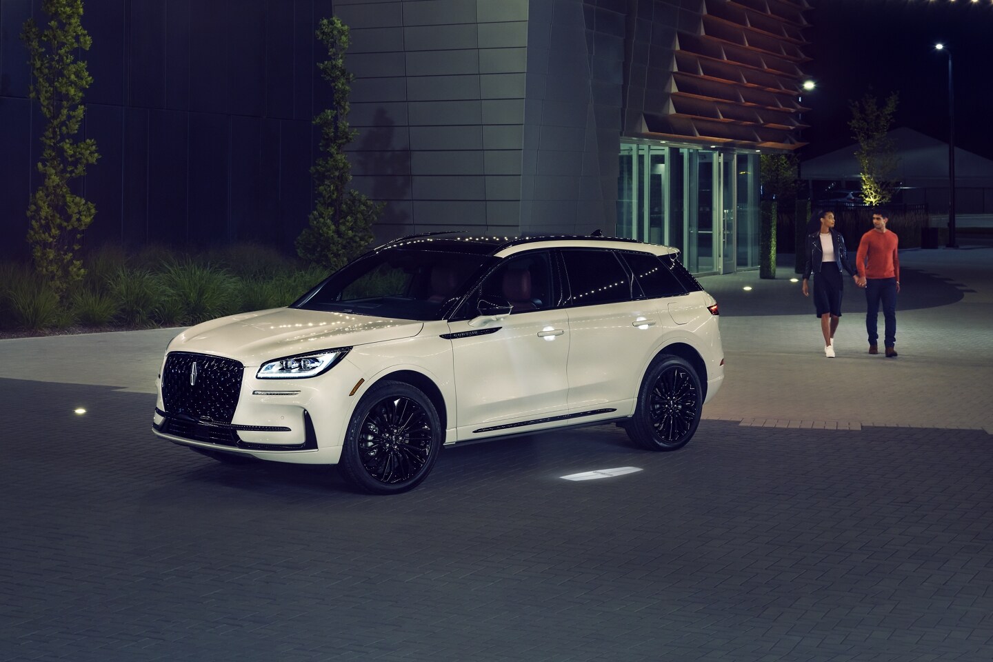 A couple approaches a 2026 Lincoln Corsair® SUV as the Lincoln Embrace illumination guides the way