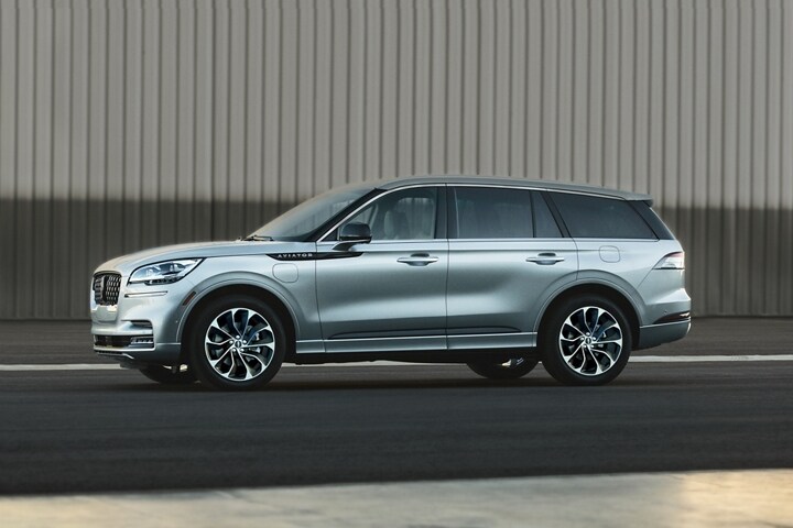Se muestra una Lincoln Aviator® 2023 estacionada al lado de un hangar de aviones privado