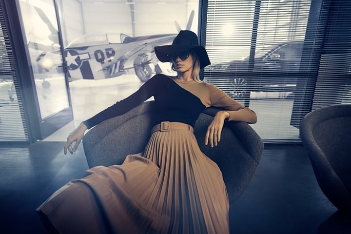 Se muestra una mujer relajándose con estilo mientras espera dentro de un hangar de aviones privado