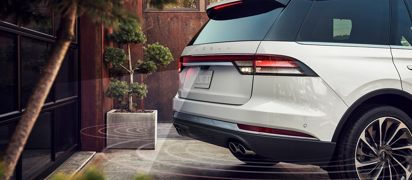 A 2023 Lincoln Aviator® is shown as it backs up toward a garage to demonstrate Reverse Brake Assist