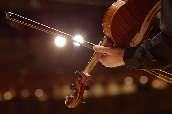 Se muestra una mano sosteniendo un violín para ilustrar el sonido musical de alerta