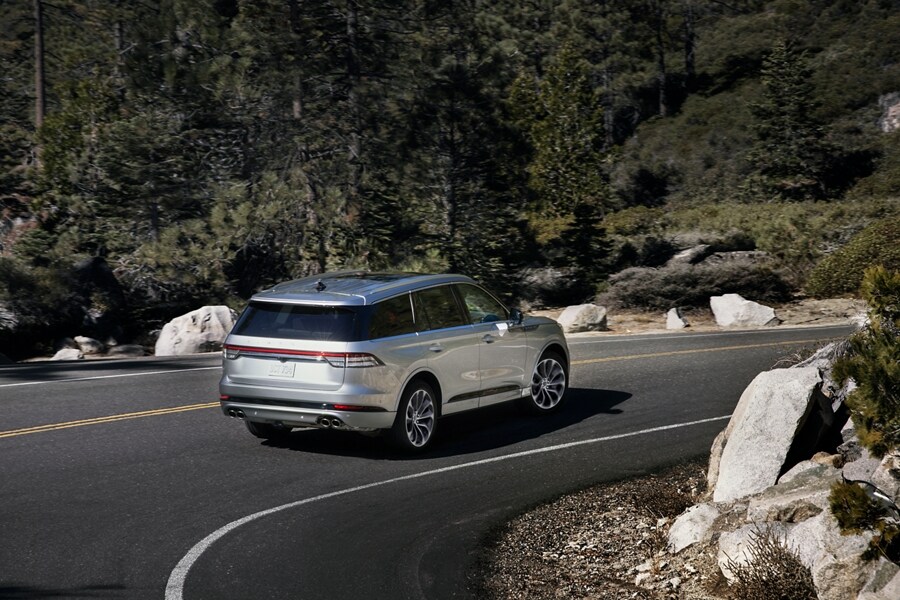 Se muestra una Lincoln Aviator® 2023 pasando por una curva cerrada en un camino de montaña