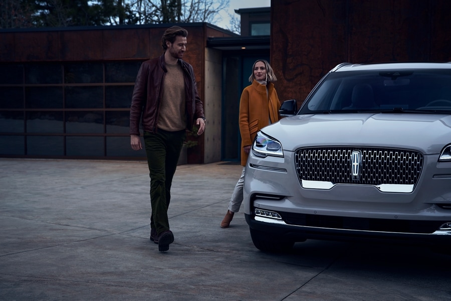 A man and a woman are shown approaching a 2023 Lincoln Aviator® SUV, which illuminates certain lights when they are close