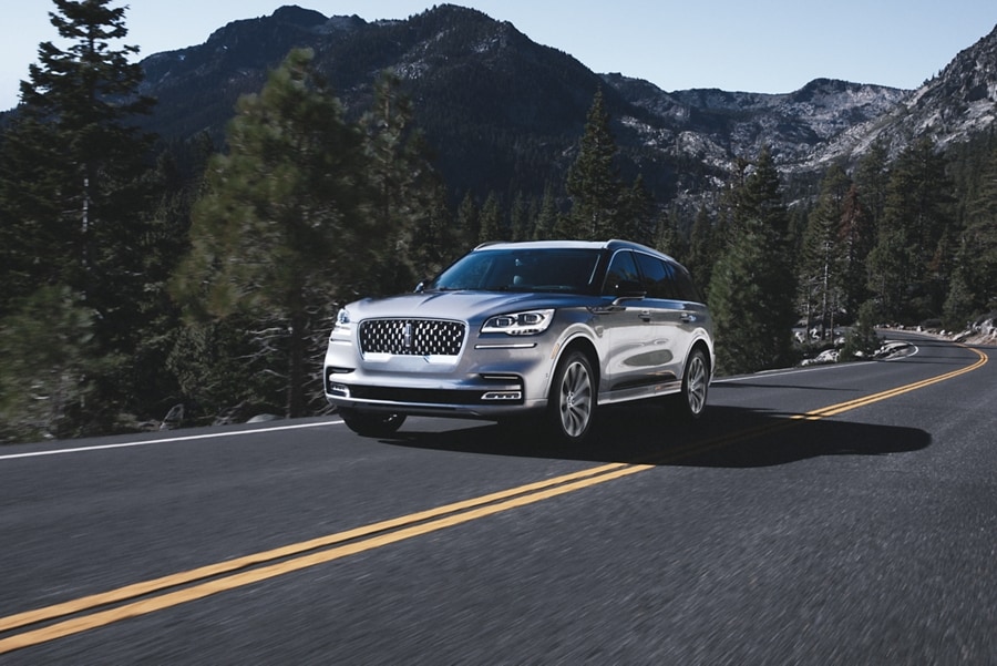 A 2023 Lincoln Aviator® is shown being driven on a tree-lined mountain road