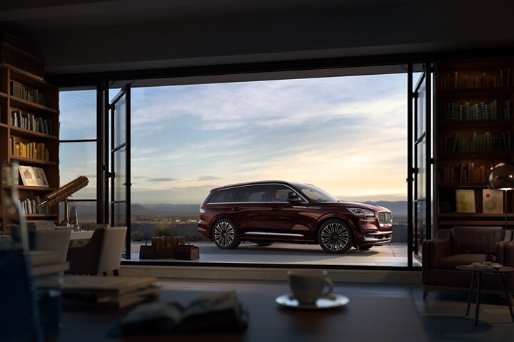 Imagen de la Lincoln Aviator® Black Label 2023 a través de las puertas abiertas del porche de un refugio en la cima de una montaña