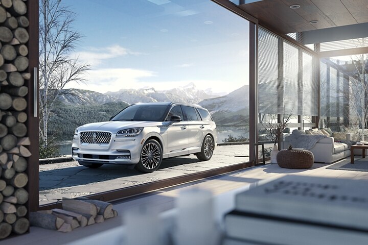 Imagen de una Lincoln Aviator® Black Label 2023 estacionada en la puerta de un refugio en la cima de una montaña con nieve