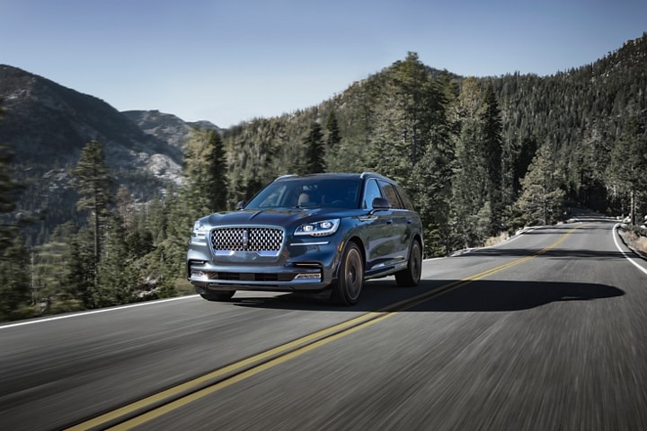 A 2023 Lincoln Aviator® Black Label model with all wheel drive is shown being driven on a mountain road