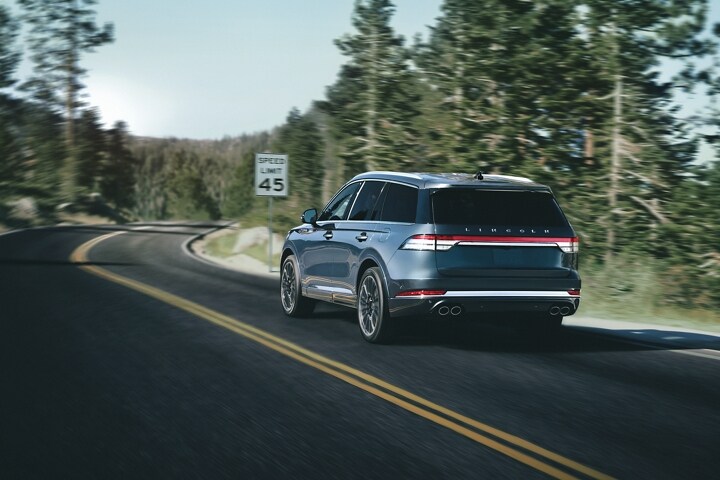 Se muestra una Lincoln Aviator® 2023 pasando por un camino de montaña mientras se aproxima a un letrero de límite de velocidad