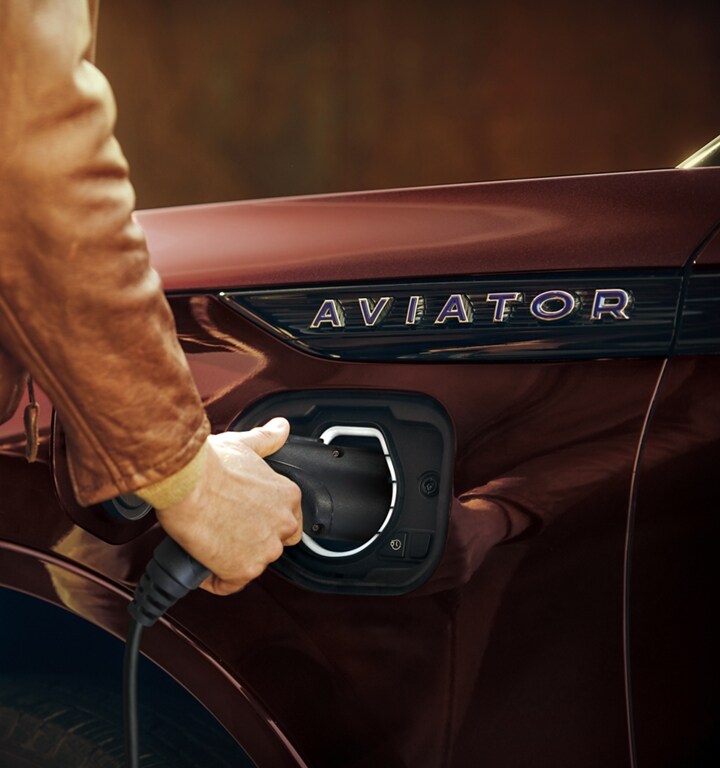 A person is shown disconnecting the at home charger from a 2023 Lincoln Aviator®