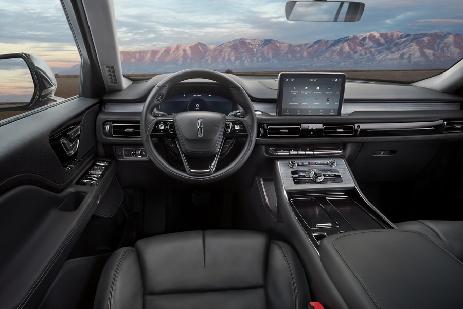 The front cabin of a 2023 Lincoln Aviator® is shown with a remote mountain range appearing through the windshield