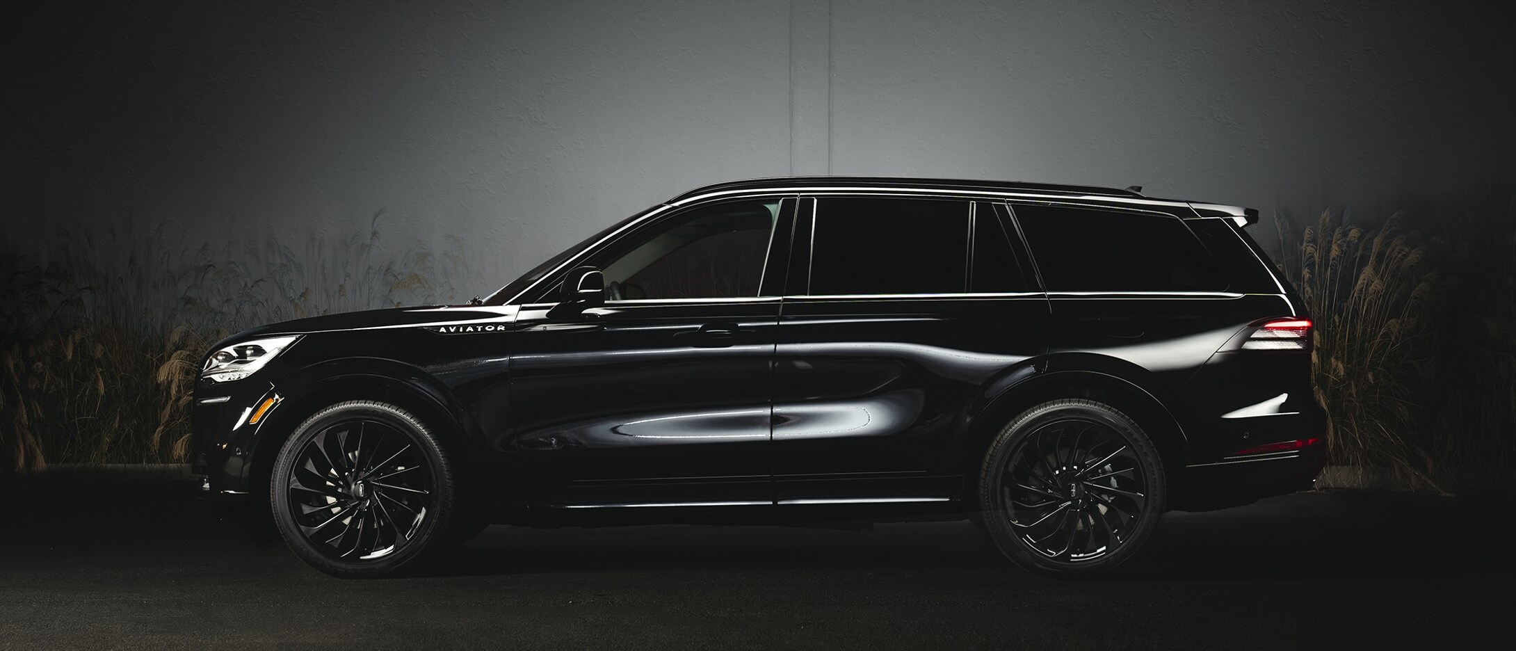Se muestra un modelo Lincoln Aviator® Grand Touring 2023 estacionado junto a un hangar de aviones