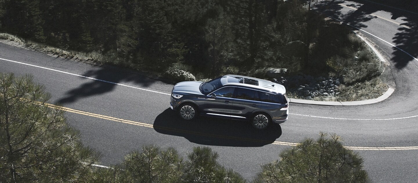 A 2024 Lincoln Aviator® SUV is being driven on a winding mountain road