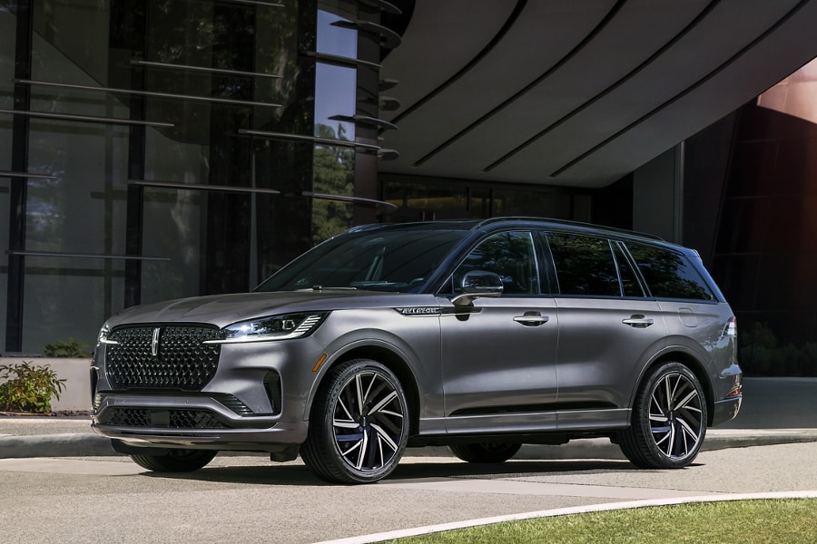 A 2025 Lincoln Black Label Aviator® SUV with an Asher Gray exterior is parked in front of a building