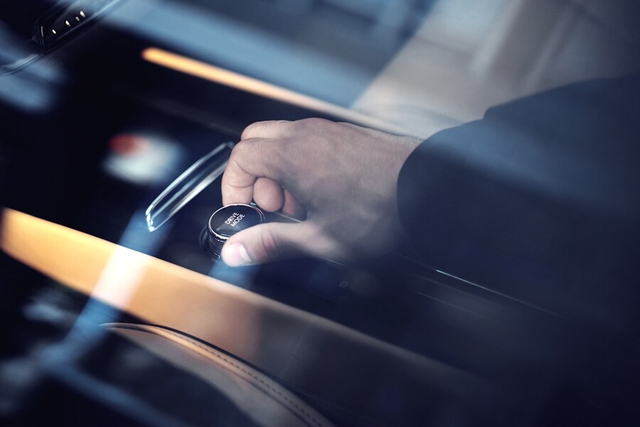 A través de la ventana de una SUV Lincoln Corsair® 2023, se muestra una mano que gira la perilla de modos de conducción