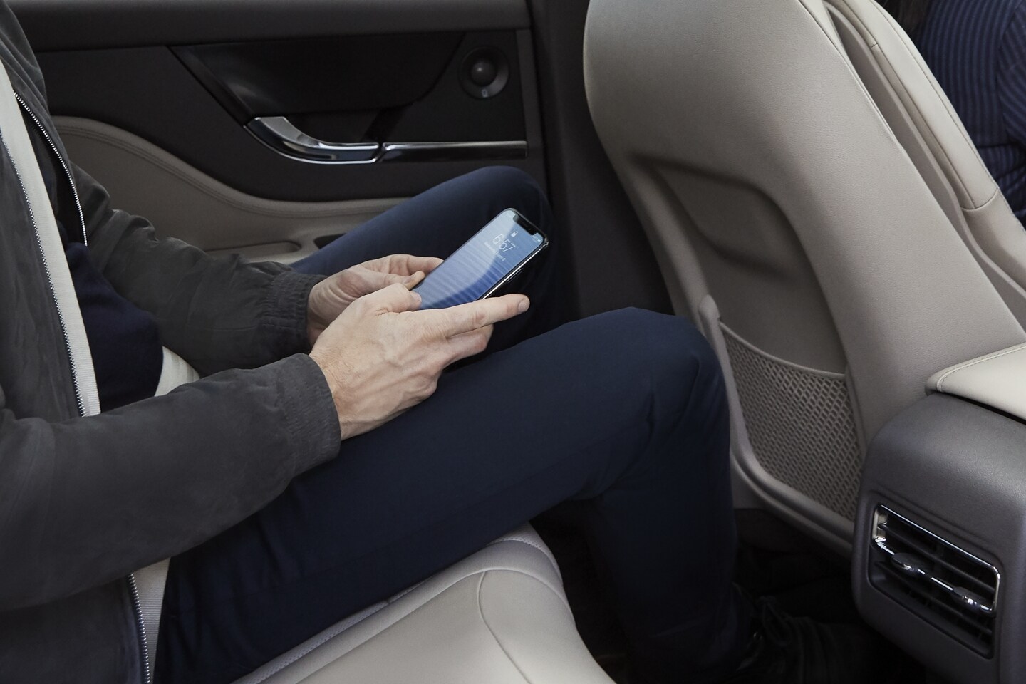 A rear-seat passenger of a 2023 Lincoln Corsair® SUV uses his smartphone